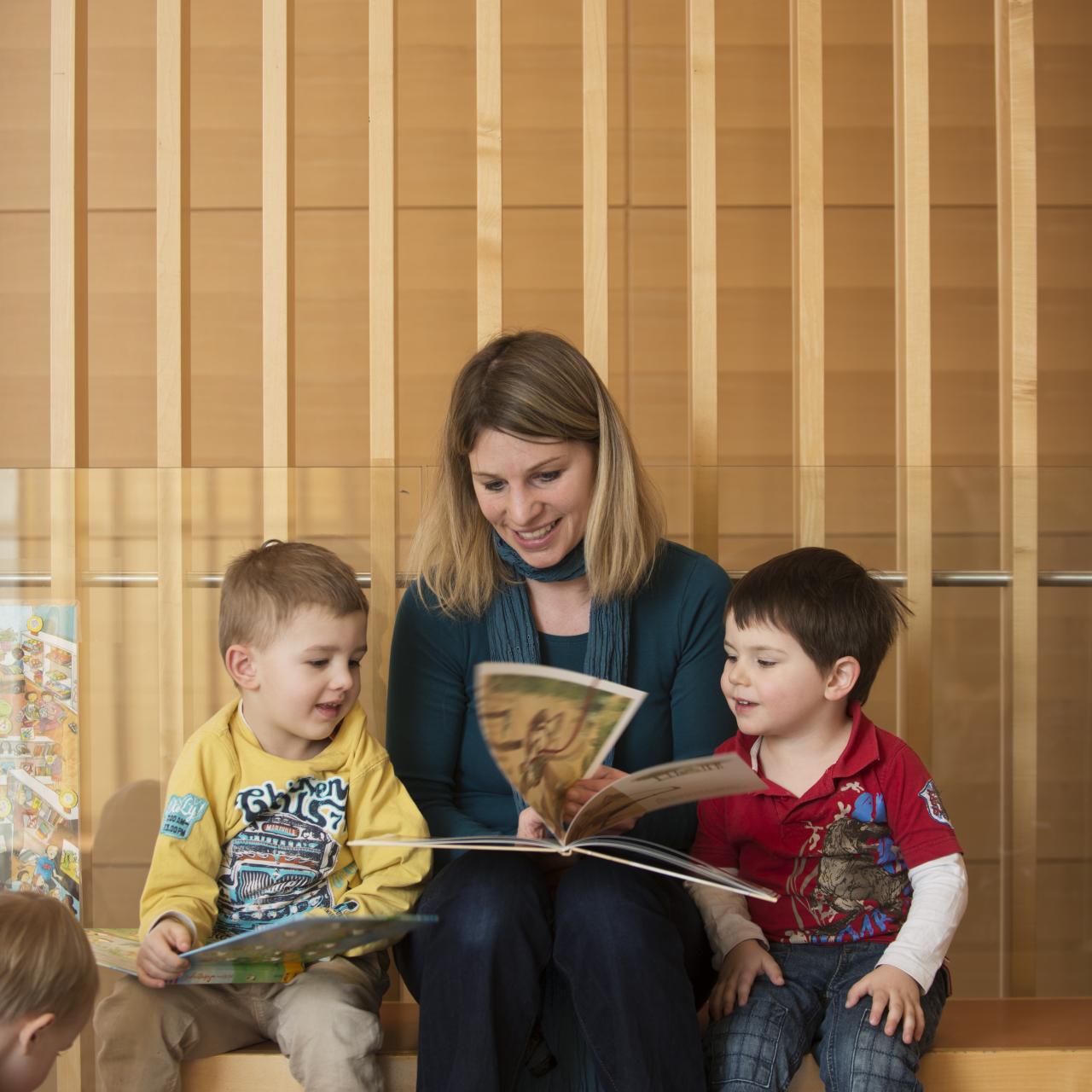 Frau liest mit Kindern